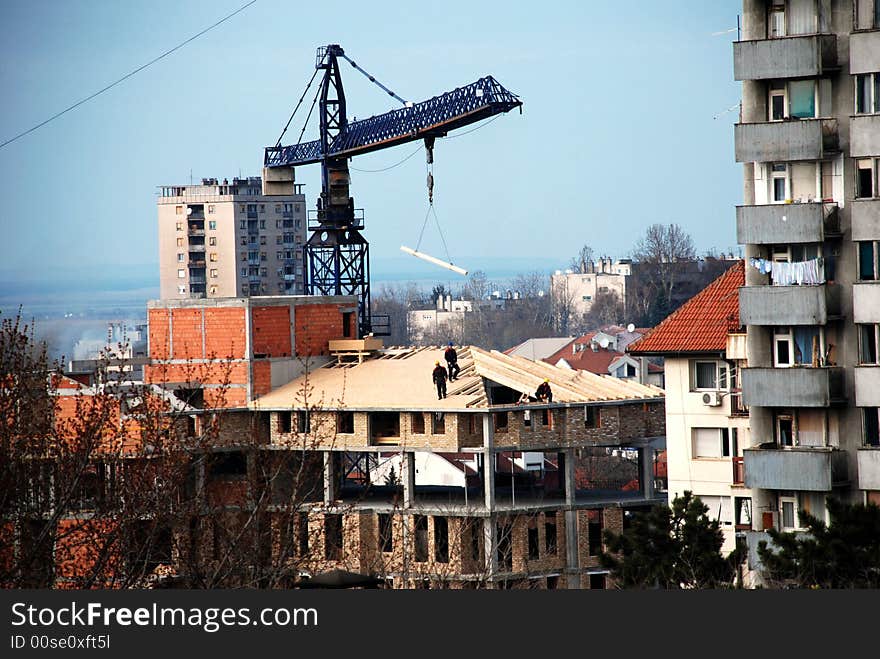 Workers on a roof of brick building with lifting crane. Workers on a roof of brick building with lifting crane
