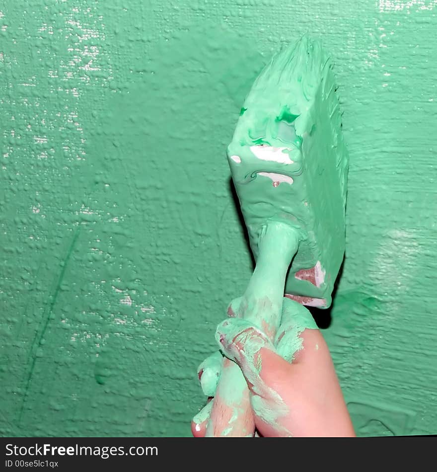 Kid' hand with a brush painting a wall is covered with green paint. Kid' hand with a brush painting a wall is covered with green paint