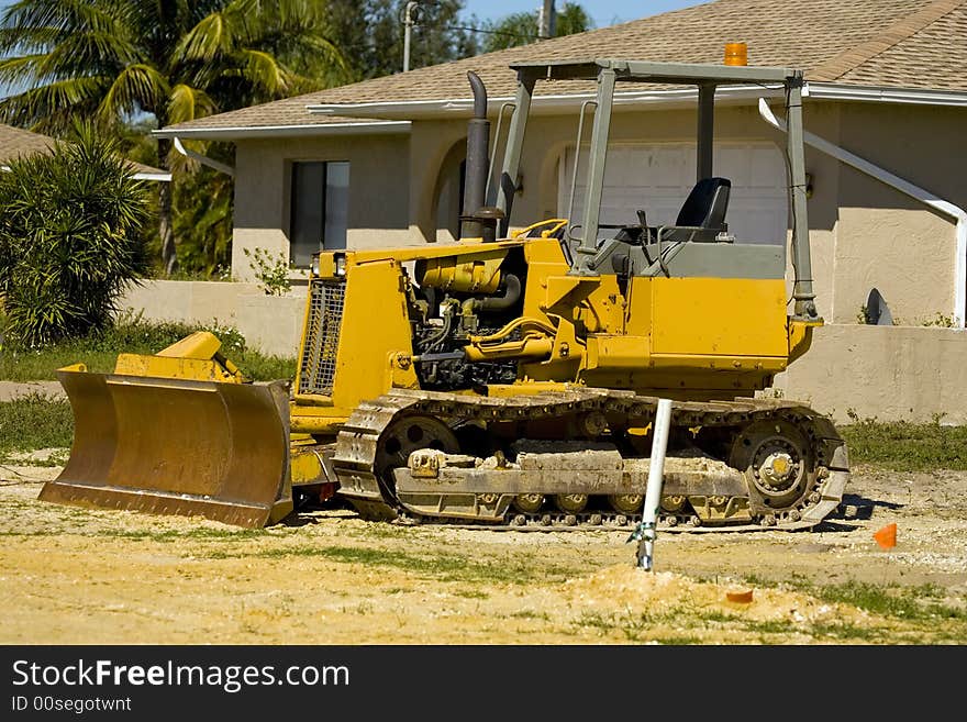 A small bulldozer at rest at a job site with the blade rusting. A small bulldozer at rest at a job site with the blade rusting