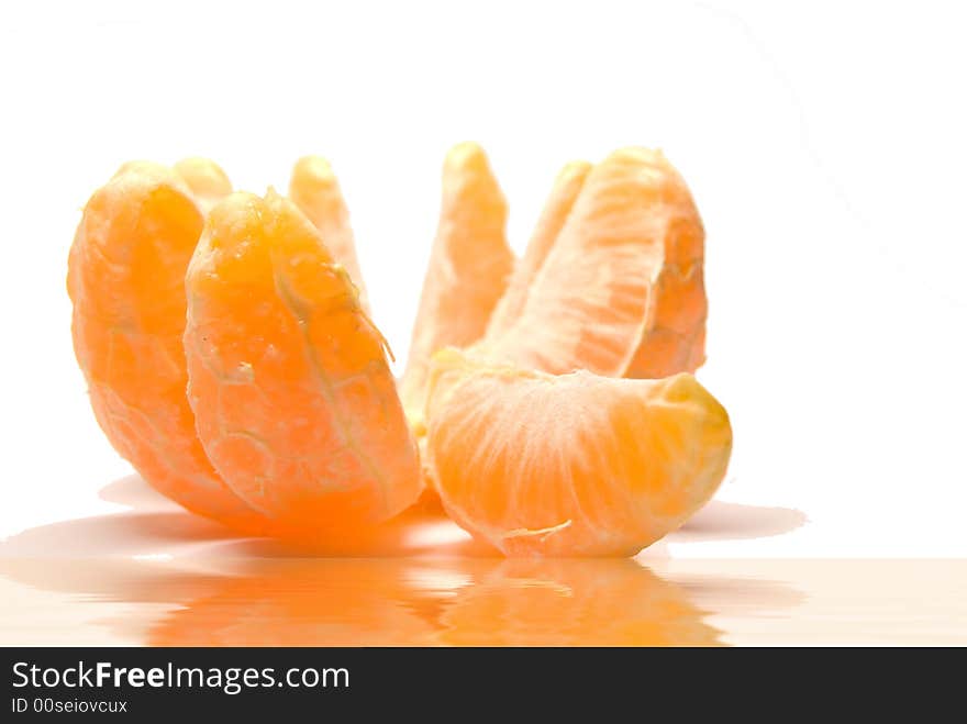 The beautiful orange ripe tangerine of a segment is reflected in water in a white background. The beautiful orange ripe tangerine of a segment is reflected in water in a white background