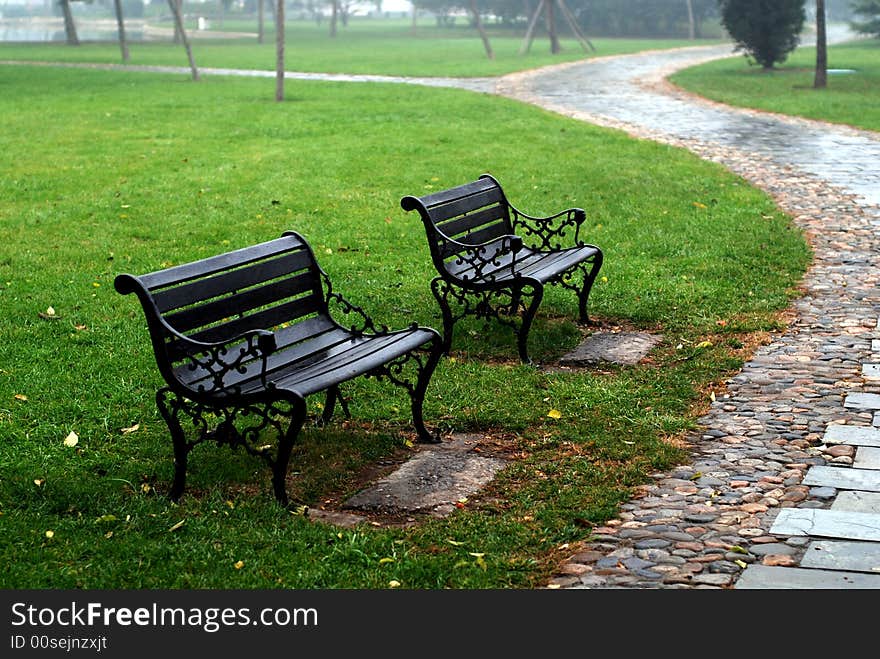 This is a stone road in the Park.It is two chair side the path.After a rain,thd path is waterish. This is a stone road in the Park.It is two chair side the path.After a rain,thd path is waterish.