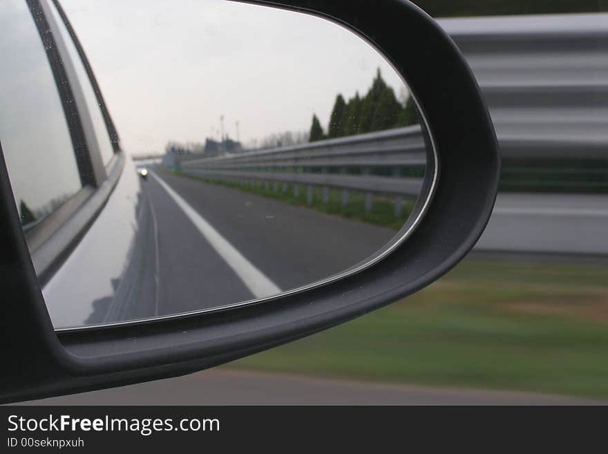 Car driving, side of the road reflecting in the mirror