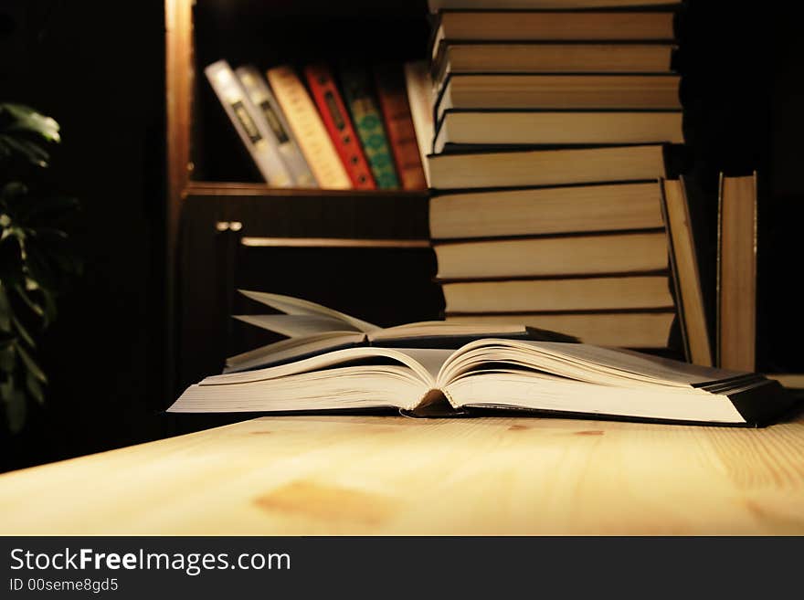 Various books on wooden table on background with evening home interior. Various books on wooden table on background with evening home interior