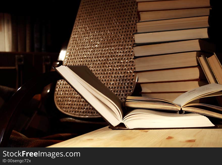 Various books on wooden table on background with evening home interior. Various books on wooden table on background with evening home interior