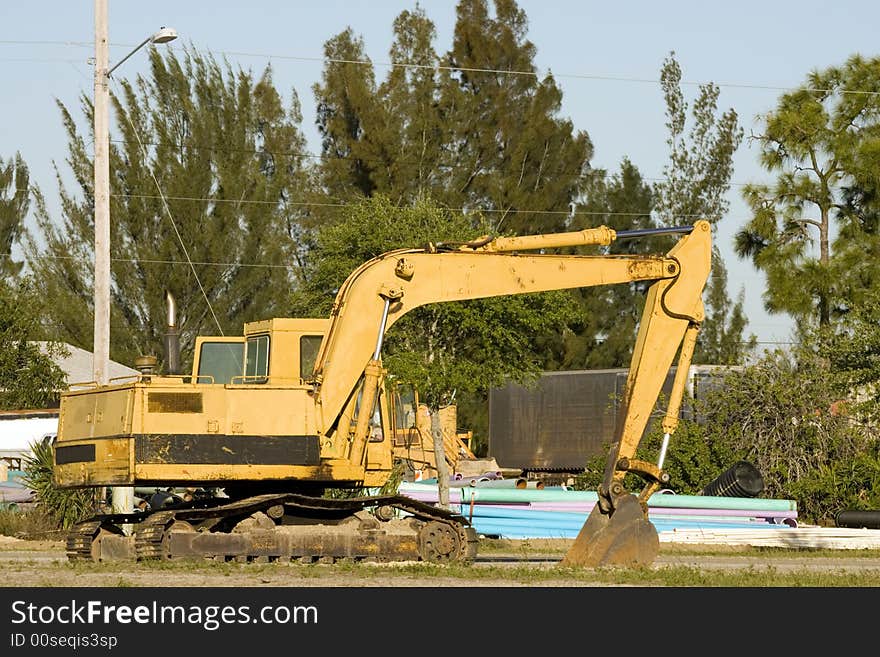 A backhoe at a job site while the operator is in a meeting