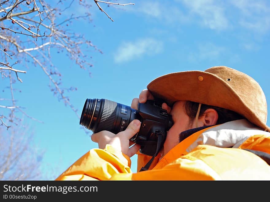 Young man taking picture outdoor, blue sky in background. Young man taking picture outdoor, blue sky in background.