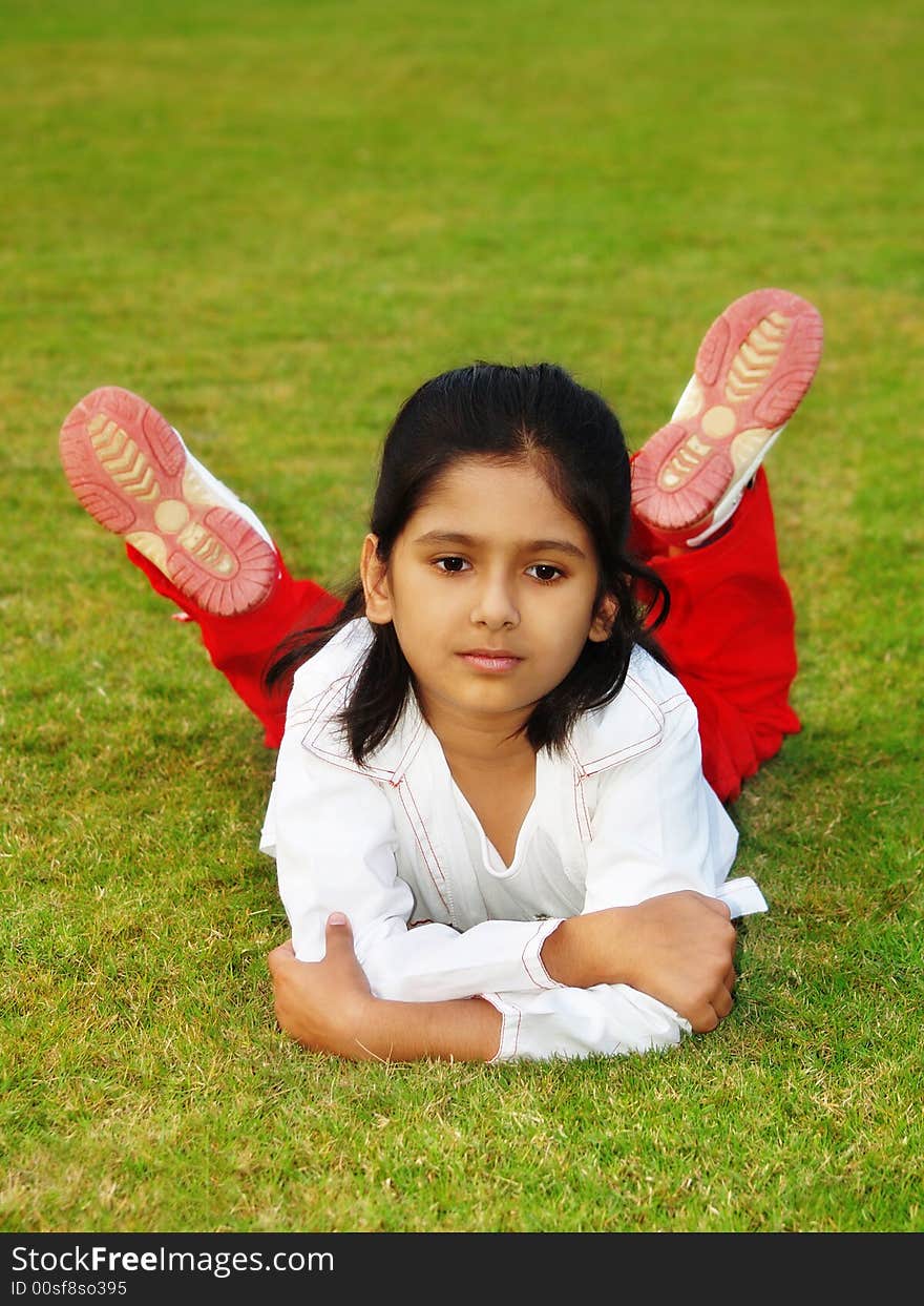 A cute Indian girl lying on a green grass lawn. A cute Indian girl lying on a green grass lawn.