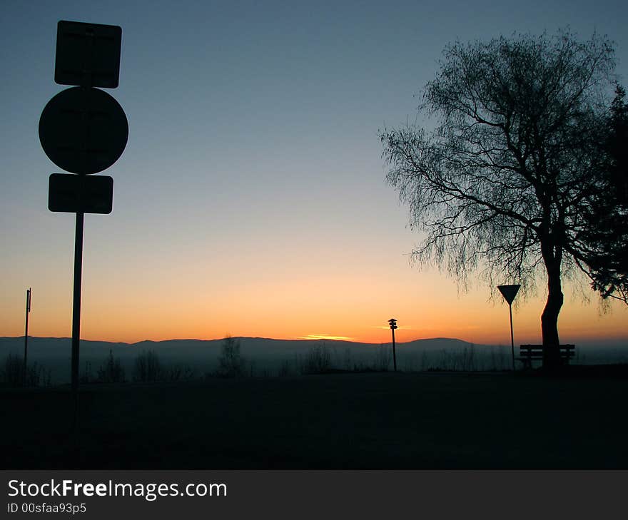 Sunset and the silhouette of the tree and the traffic sing. Sunset and the silhouette of the tree and the traffic sing