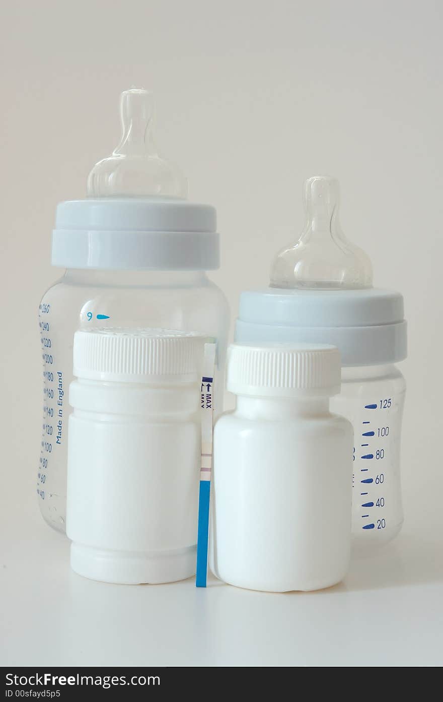 Confirmative pregnancy test, two drug's (vitamins) bottles and two small baby's bottles. Confirmative pregnancy test, two drug's (vitamins) bottles and two small baby's bottles.