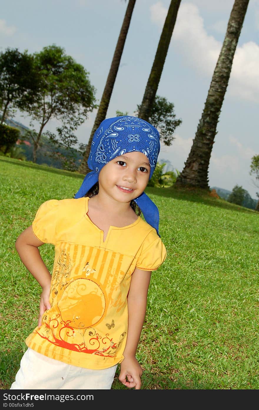A little girl wearing bandana covering her head at the park. A little girl wearing bandana covering her head at the park.