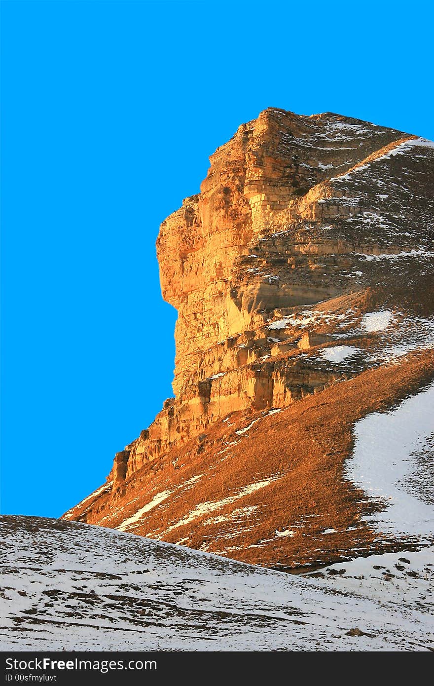 Red rock in a snow on a background of the blue sky