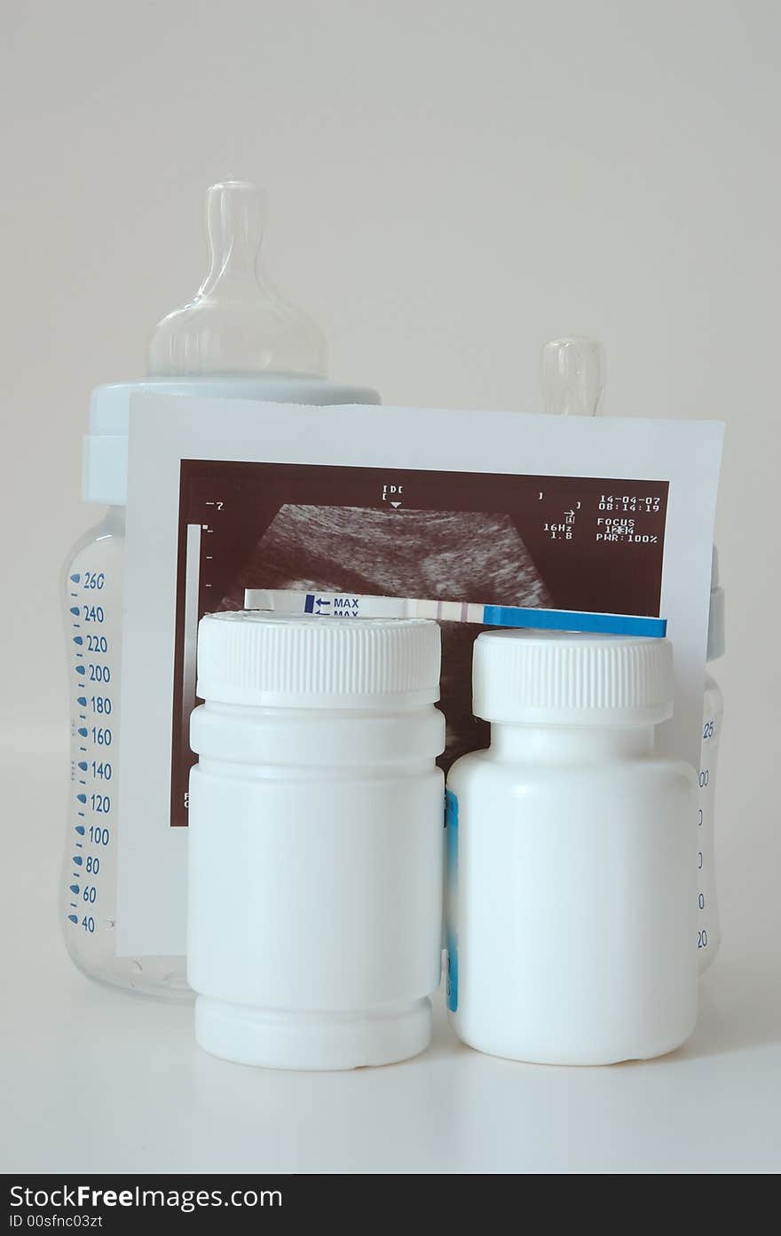 Confirmative pregnancy test, two drug's (vitamins) bottles, two small baby's bottles and ultrasound picture. Confirmative pregnancy test, two drug's (vitamins) bottles, two small baby's bottles and ultrasound picture.