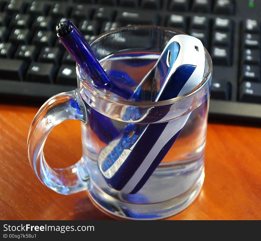 Mobile phone and the pen in a glass of water. Mobile phone and the pen in a glass of water