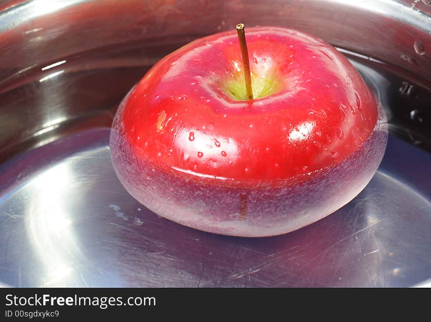 Red Apple floating around in a pot with water. Red Apple floating around in a pot with water.