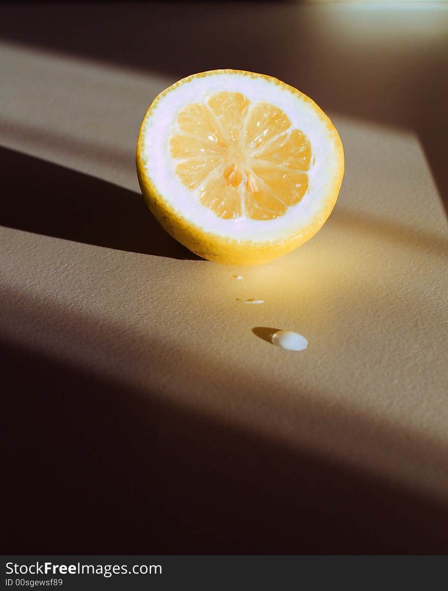 A lemon and a drop with a warm lateral light that emphasizes shadows. Different from usual lemon shots. A lemon and a drop with a warm lateral light that emphasizes shadows. Different from usual lemon shots