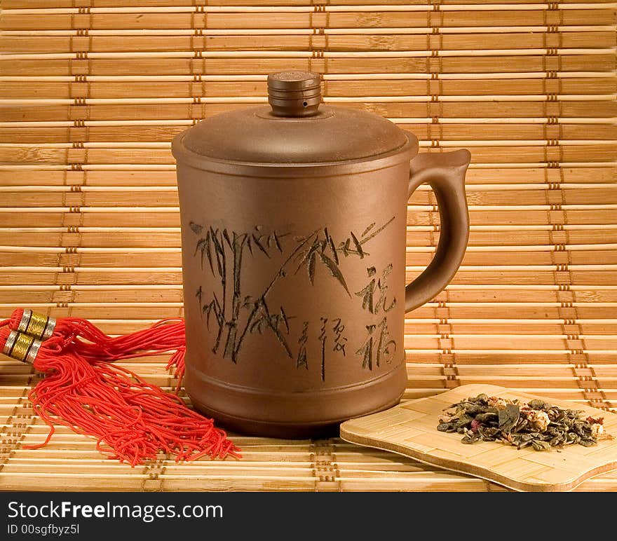 Clay cup of tea with tea leafs on bamboo background