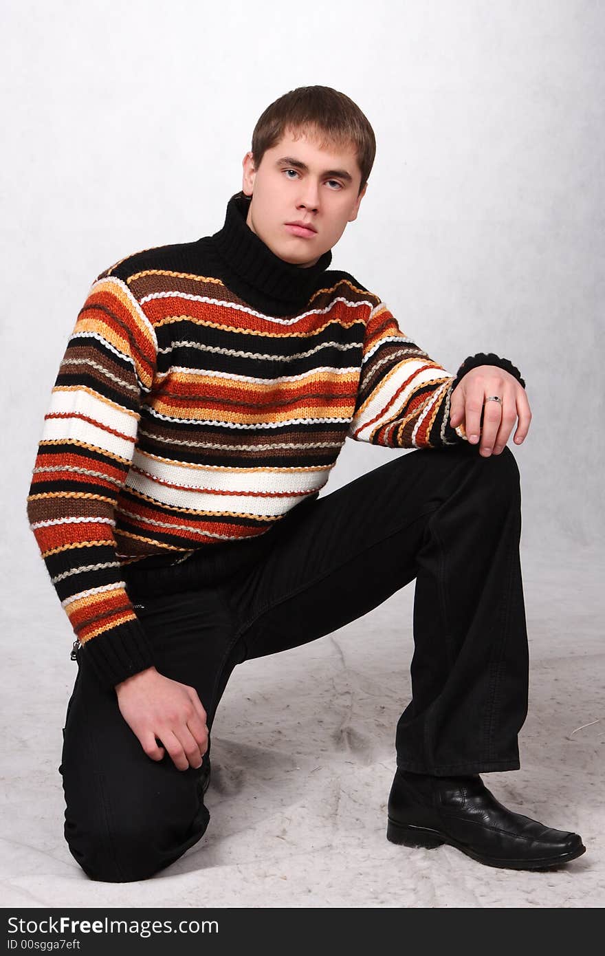 The young guy in jeans and a sweater standing on one knee, with a ring on a finger. The young guy in jeans and a sweater standing on one knee, with a ring on a finger