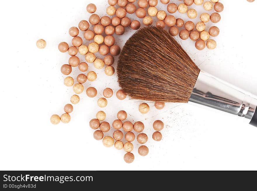 Bronzing pearls and thick brush on white background