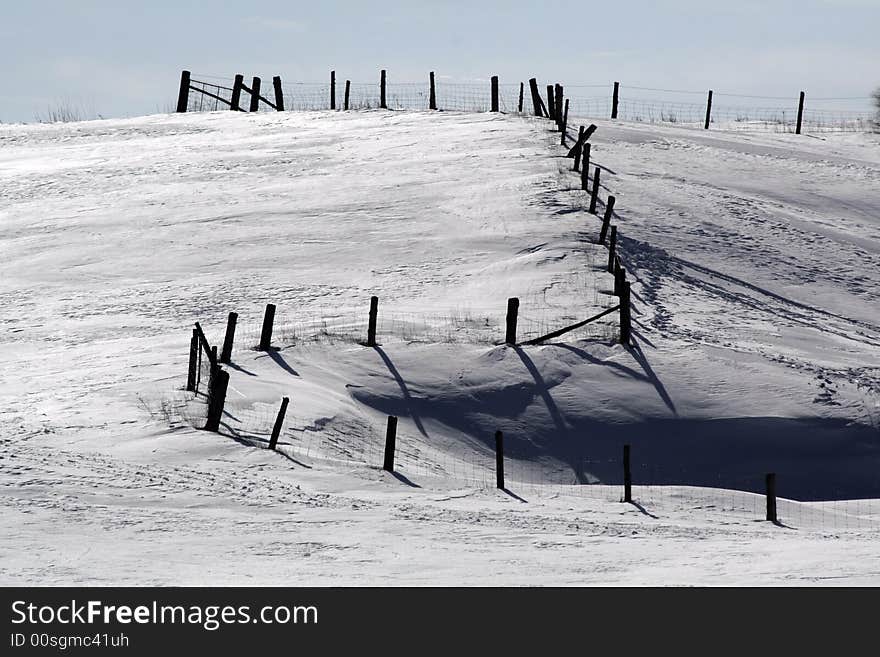 Winding fence in the snow on a hill. Winter landscape.