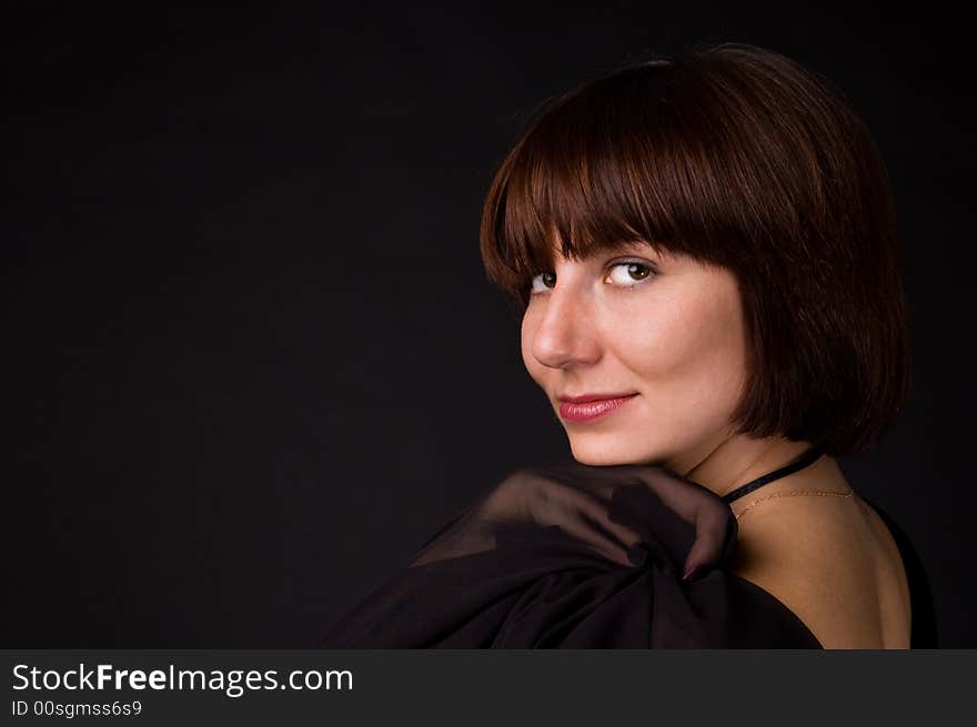 The woman in a black dress on a black background