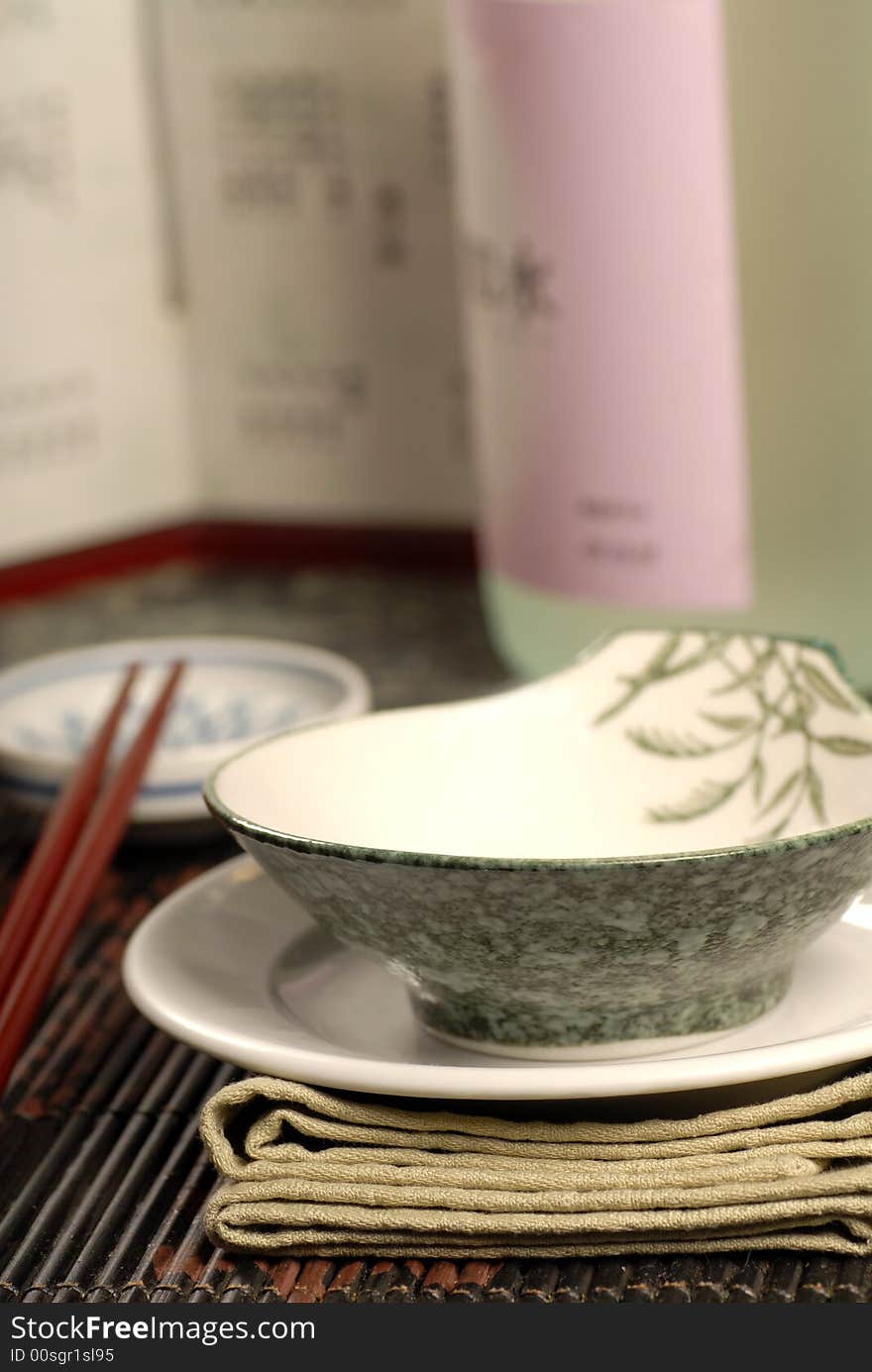 Asian restaurant table setup with sake bottle in background. Asian restaurant table setup with sake bottle in background