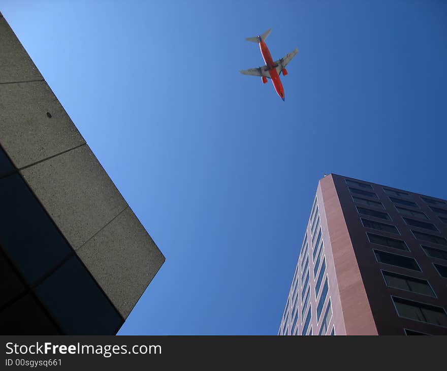 Looking up between buildings at airplane flying over city