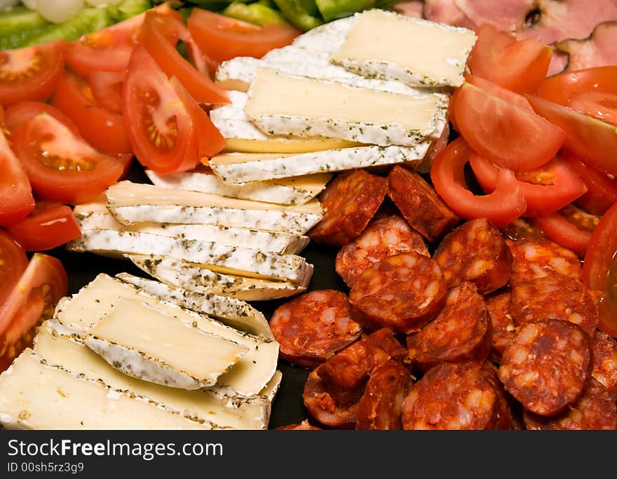 Closeup of cheese, cold meat and fresh vegetables. Closeup of cheese, cold meat and fresh vegetables