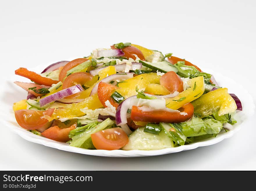 Salad from fresh vegetables on a white plate on a white background