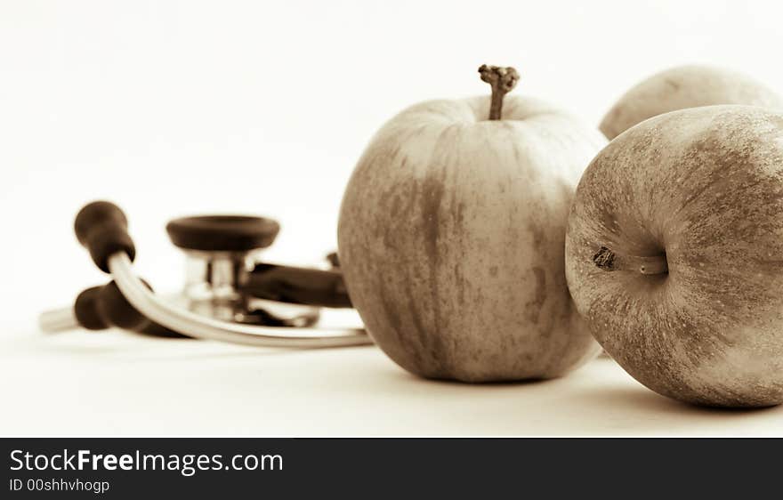 Still life of three apples and an out of focus stethoscope suggesting apples keeping away the doctor. Still life of three apples and an out of focus stethoscope suggesting apples keeping away the doctor.