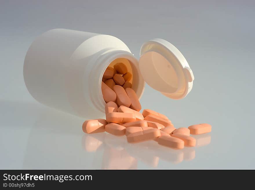 Medicine pills with a white bottle on a grey background. Close-up