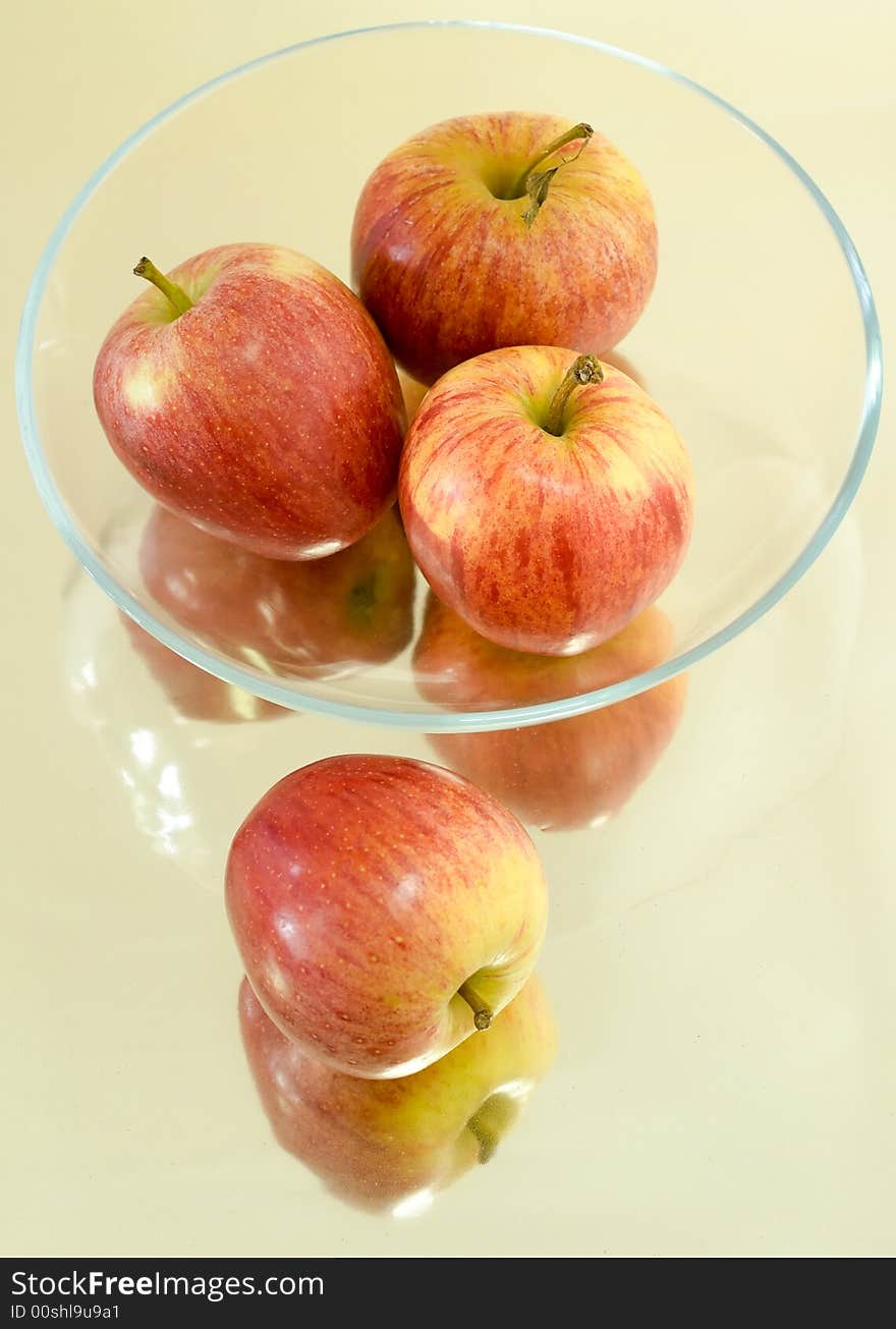 Still life of apples in a shallow glass bowl on a reflective surface. Still life of apples in a shallow glass bowl on a reflective surface