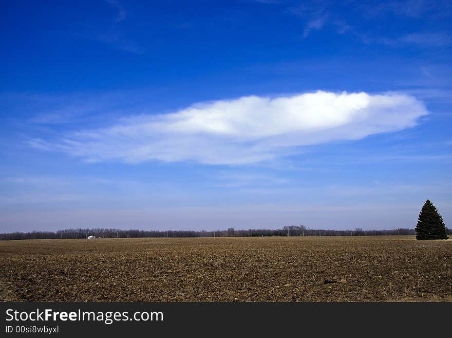 Winter cold day countryside vista with heavy browns fields and floating cloud in brith blue sky. Winter cold day countryside vista with heavy browns fields and floating cloud in brith blue sky