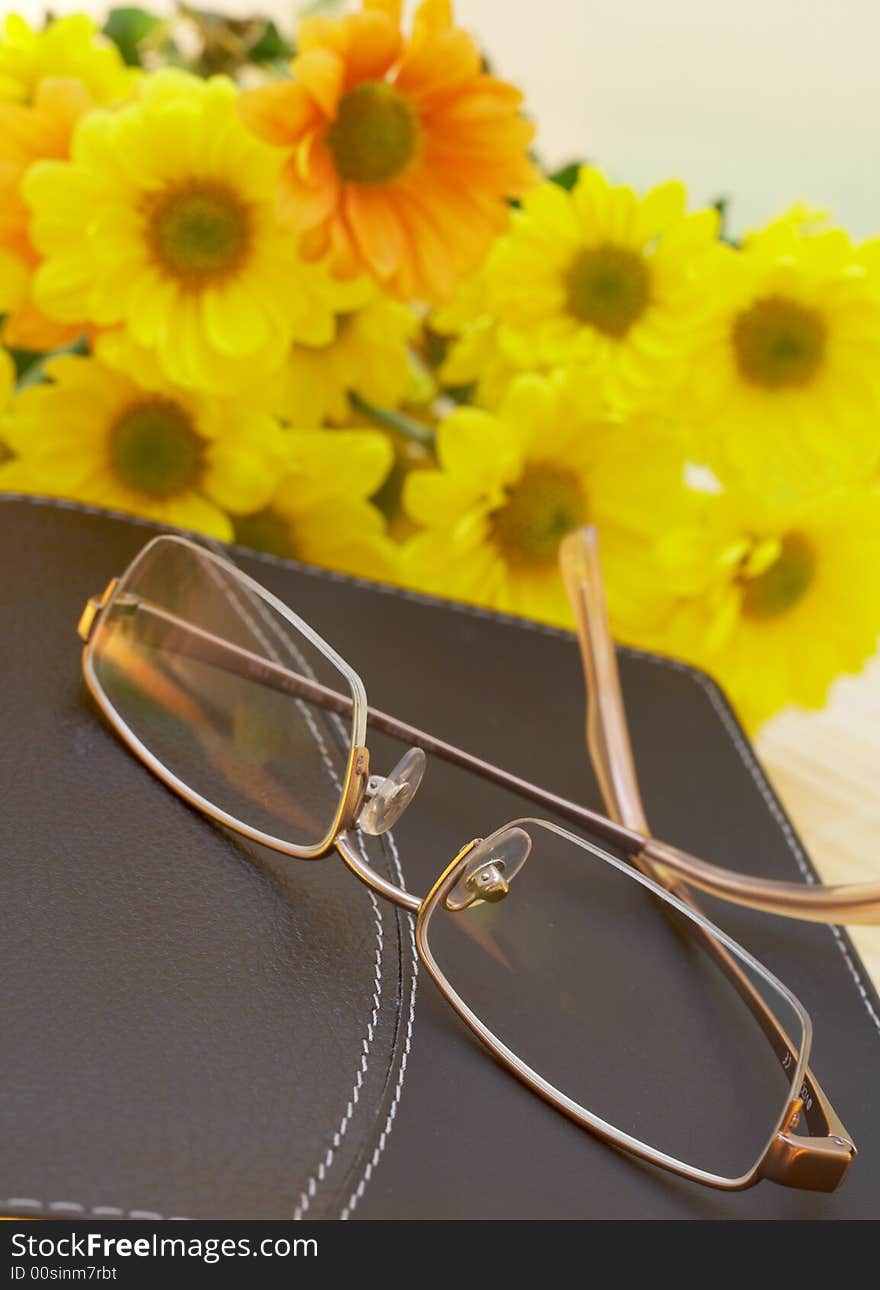 Closed Bible with glasses and spring flowers in the background. Closed Bible with glasses and spring flowers in the background