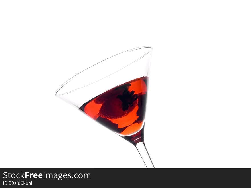 A tilted view of strawberry martini with a strawberry on white. A tilted view of strawberry martini with a strawberry on white