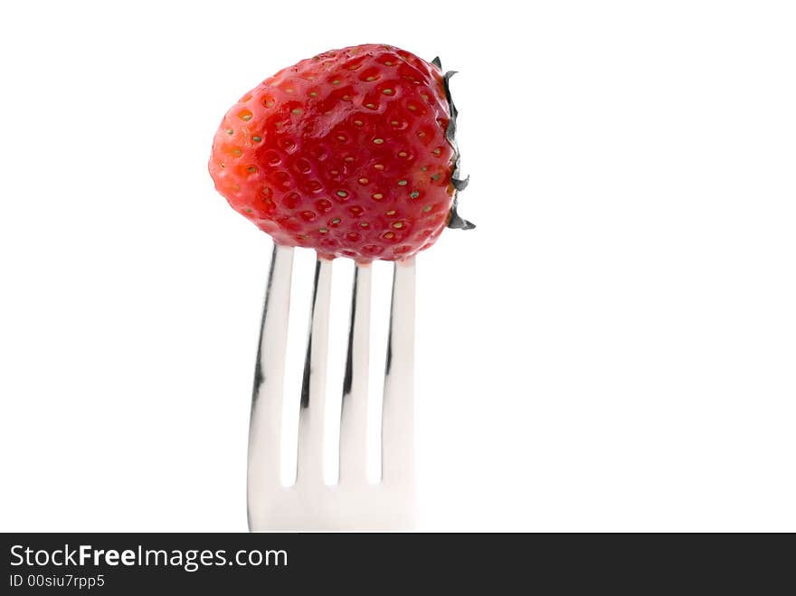 A fresh red strawberry on a fork against a white background. A fresh red strawberry on a fork against a white background