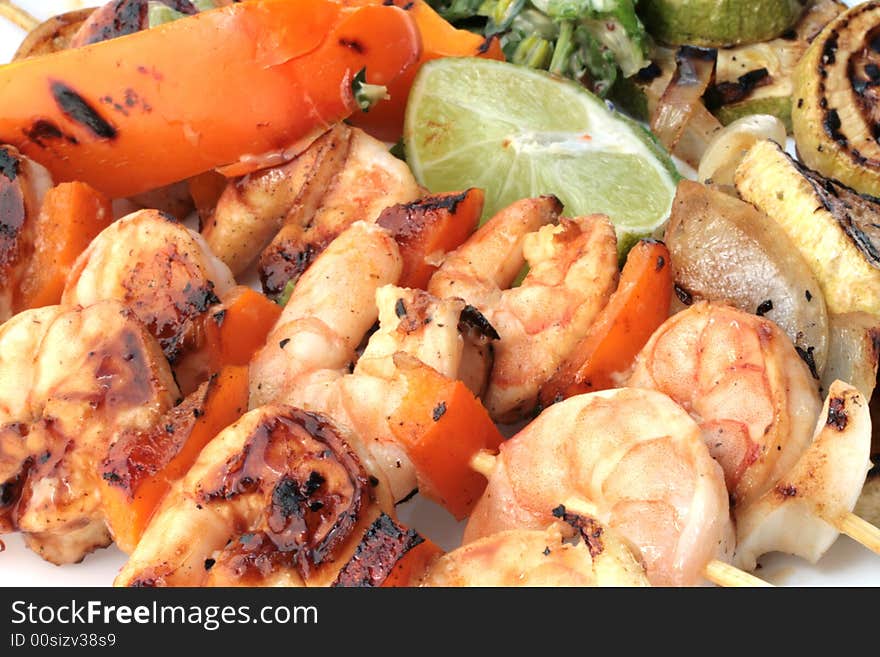 Grilled prawns on bamboo sticks served with salad and grilled vegetables in dinner setting.