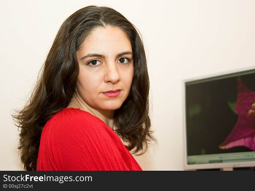 A girl, sitting near her computer, taking a little break while working. A girl, sitting near her computer, taking a little break while working