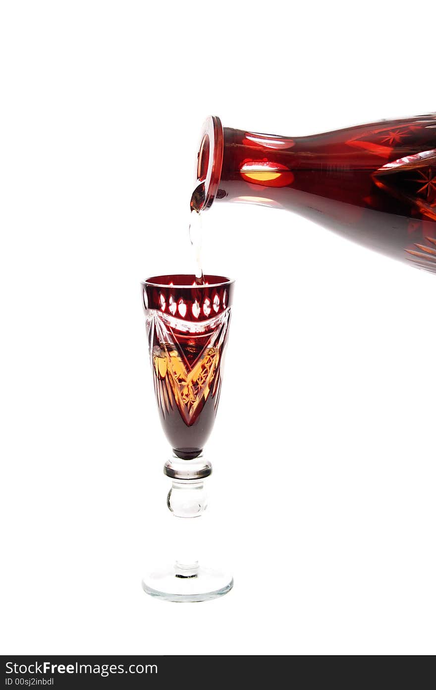 Wine-glass filling with cognac from decanter isolated on white background. Wine-glass filling with cognac from decanter isolated on white background