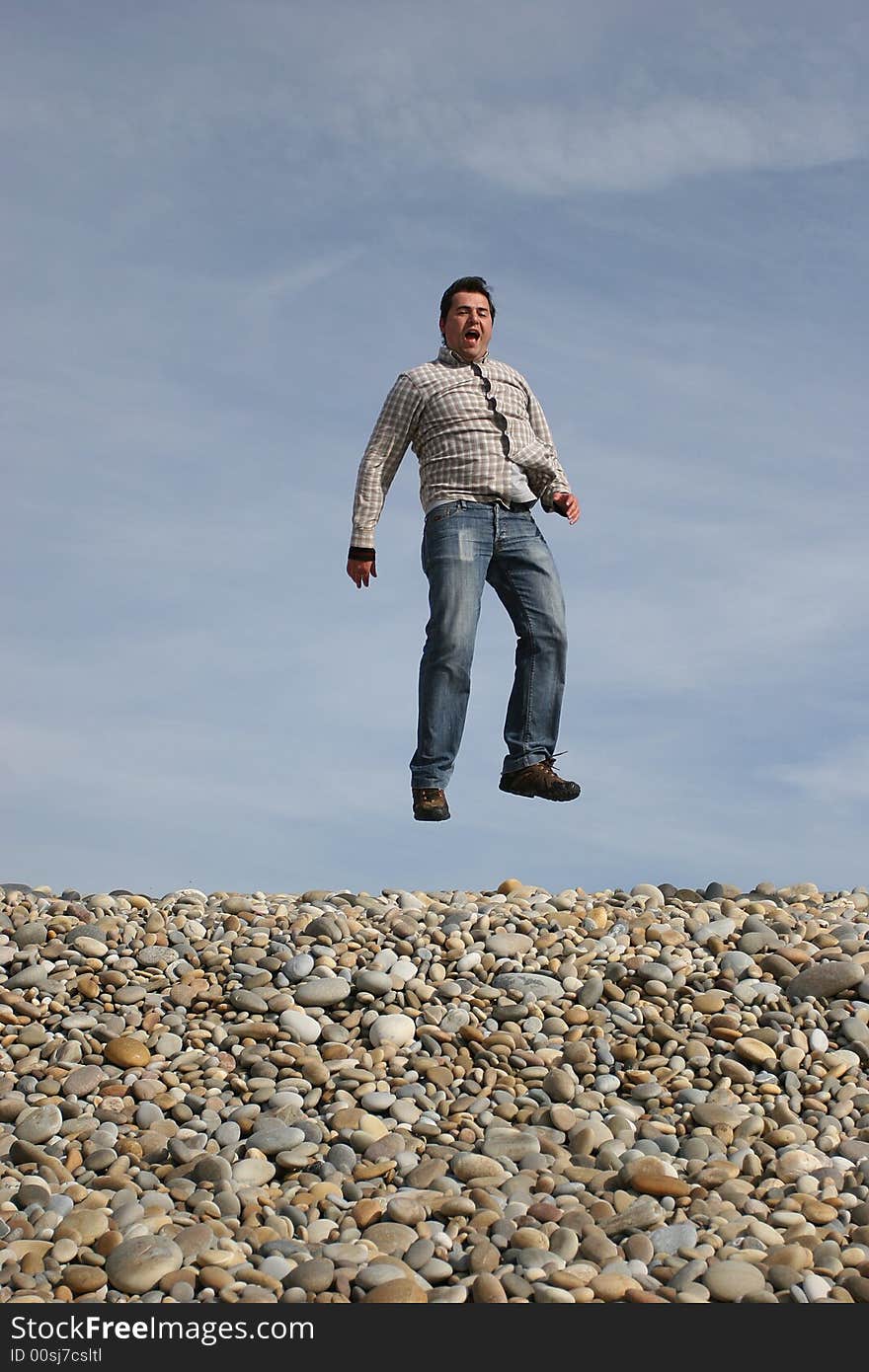 Young casual man jumping at the beach