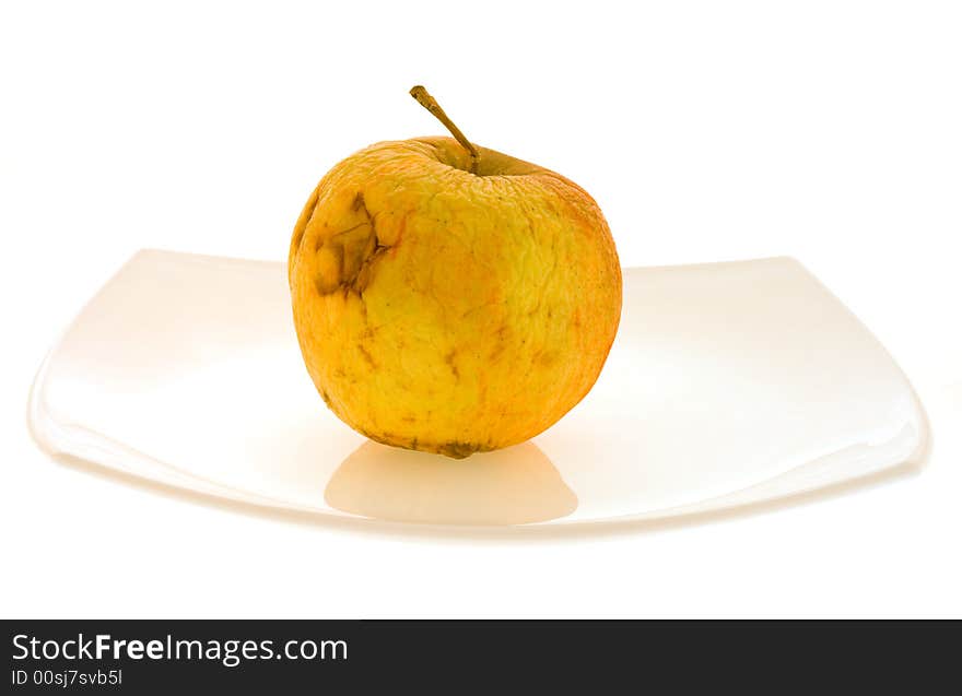 Isolated withering apple lying on the white dish