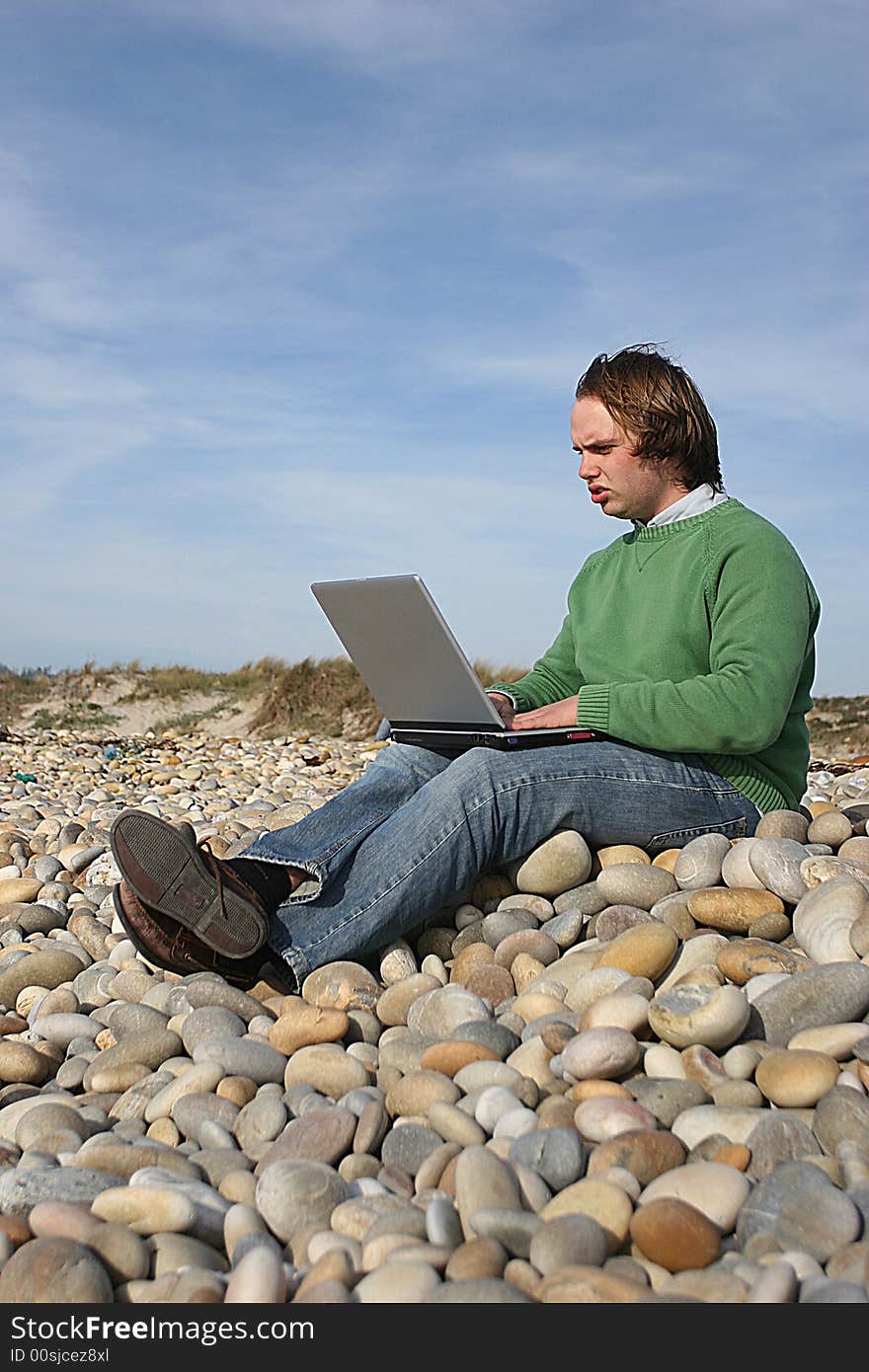 Young casual man with laptop at the beach