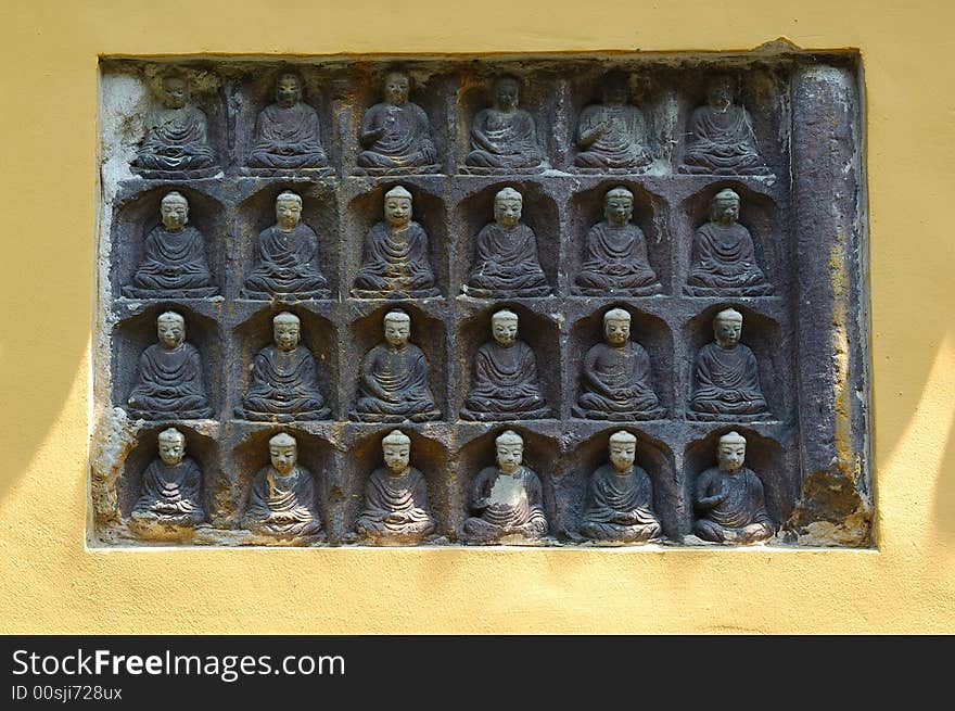 Many buddhist sculptures on the wall.