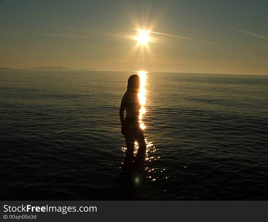 Woman silhouette against sunset in the sea