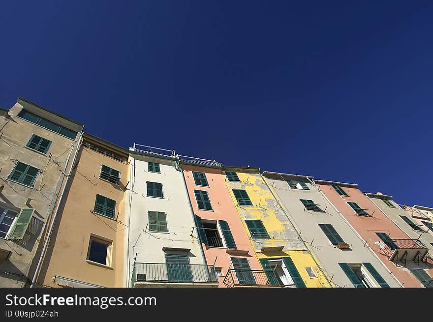 Front view of the colorful and old facades in a touristic italian port. Empty blue sky for copy space.