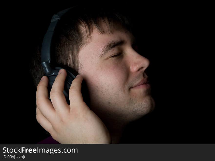 Attractive men listening music in headphones on black background