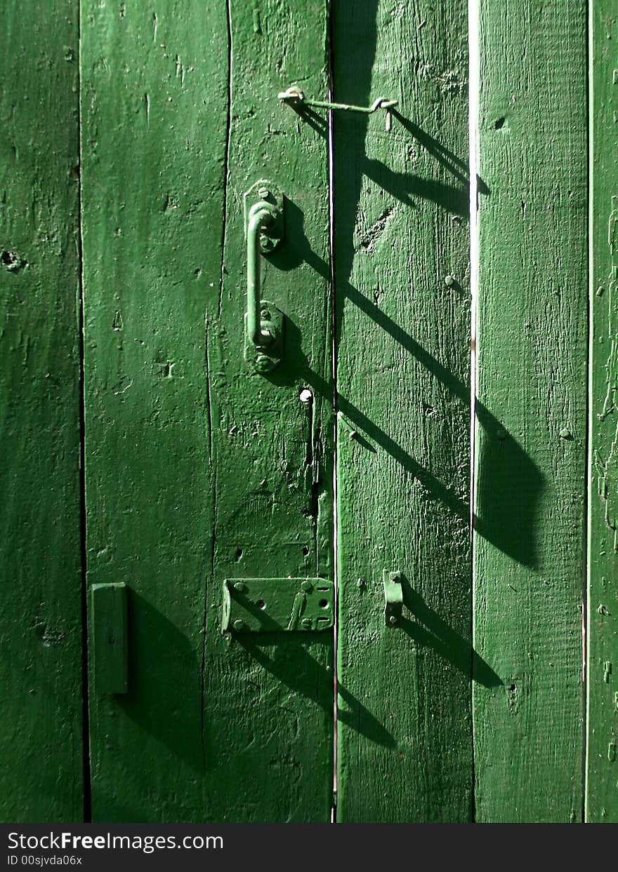 The door with bolts and a hook is green. The door with bolts and a hook is green