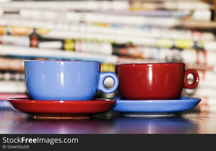 Vivid colored cups against a stck of newspapers. Vivid colored cups against a stck of newspapers