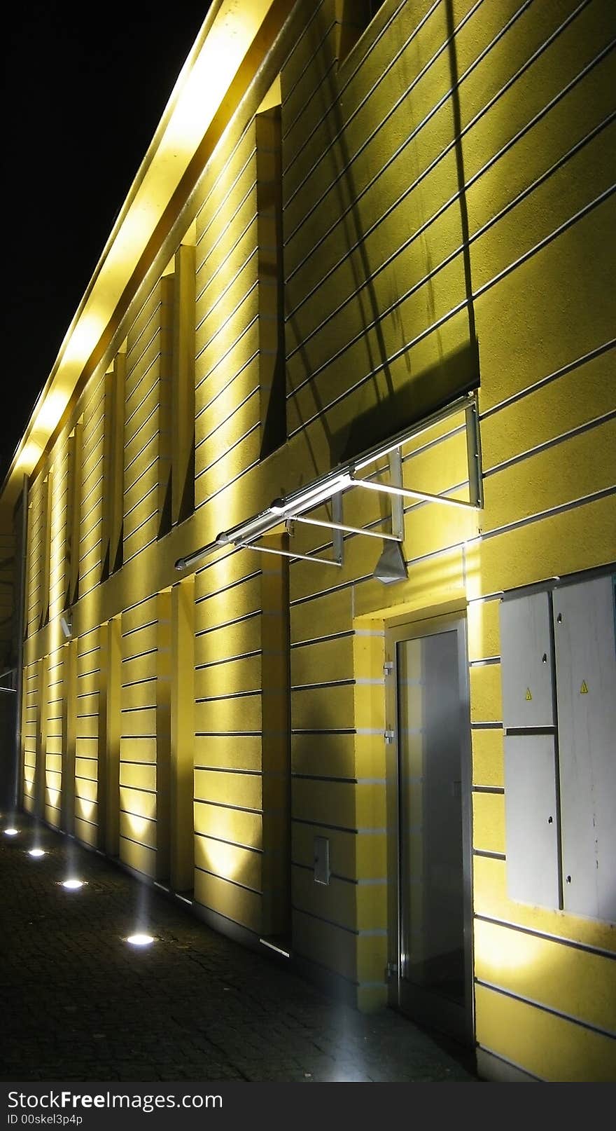 Yellow building at night with lights up toward