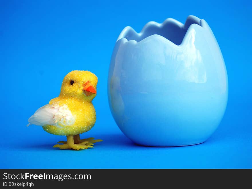 An easter toy chick with a blue egg shell with blue background. An easter toy chick with a blue egg shell with blue background