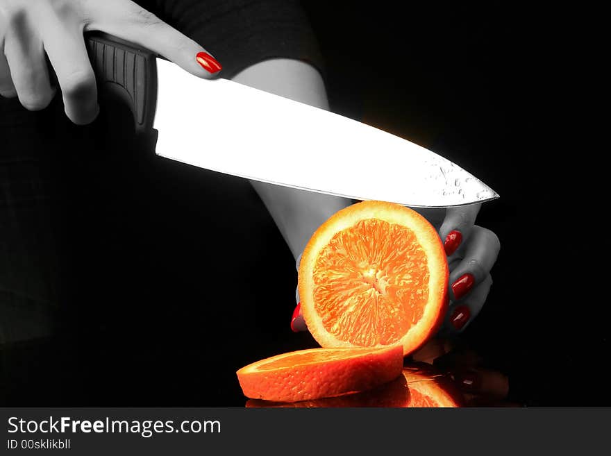 Woman is chopping orange on the black background. Woman is chopping orange on the black background